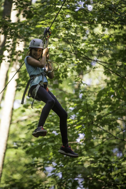 jeune fille sur tyrolienne dans parcours accrobranche