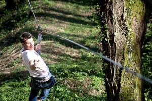 un jeune homme sur une tyrolienne au parc de loisirs vanciaventure