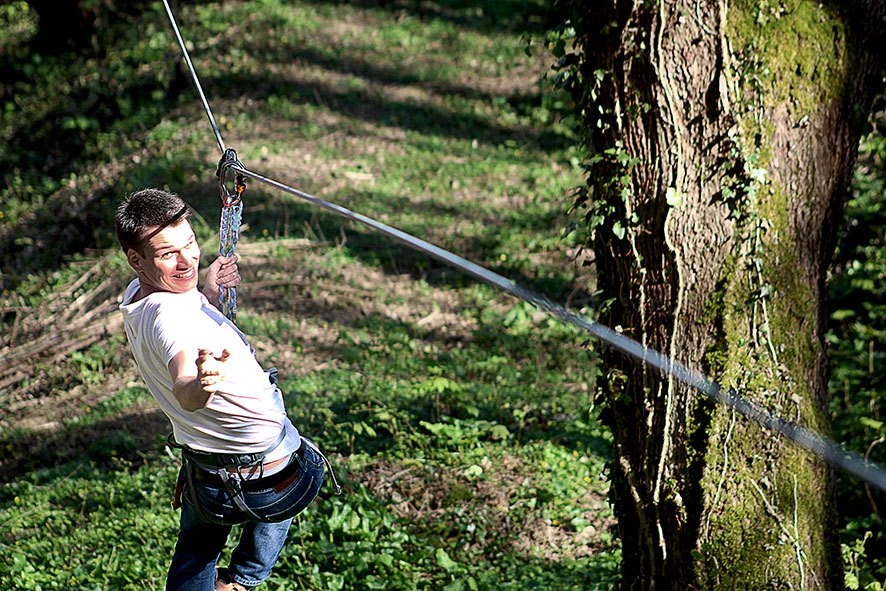 un jeune homme sur une tyrolienne au parc de loisirs vanciaventure