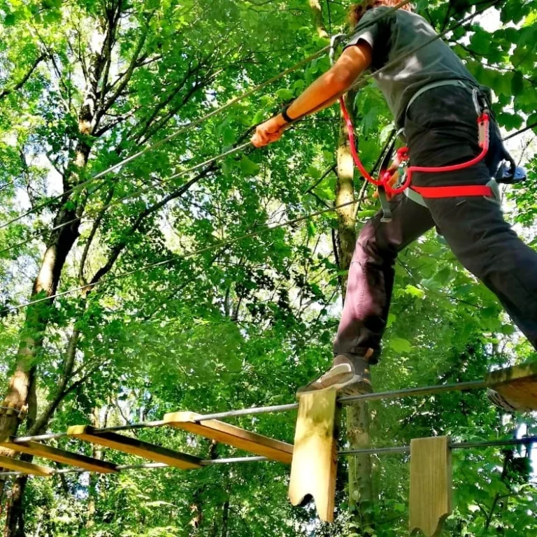 homme traverse un parcours accrobranche, une passerelle dans la forêt du fort de vancia à rillieux la pape