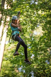 jeune fille avec casque sur tyrolienne dans un parcours accrobranche à lyon
