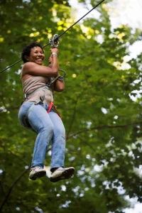 femme sur une tyrolienne entre deux arbres